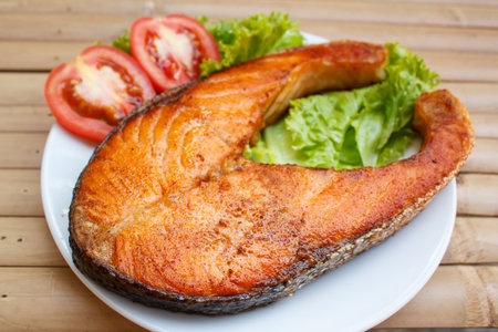 salmon steak with tomato and lettuce at restaurant.の写真素材