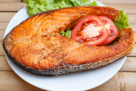 salmon steak with tomato and lettuce at restaurant.の写真素材