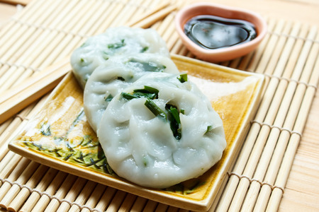 Steamed dumpling stuffed with garlic chives served with sweet black sauce.の写真素材