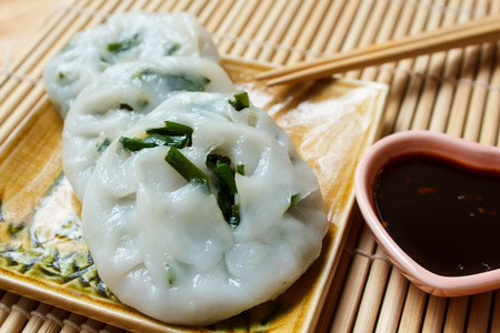 Steamed dumpling stuffed with garlic chives served with sweet black sauce.の写真素材