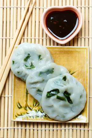 Steamed dumpling stuffed with garlic chives served with sweet black sauce.の写真素材