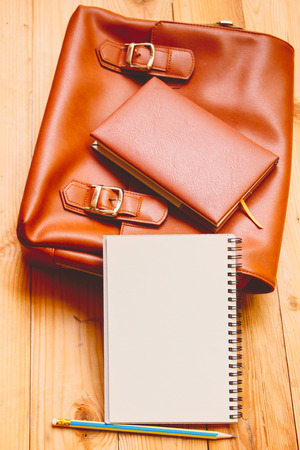 leather female bag with note book on wood background.の写真素材