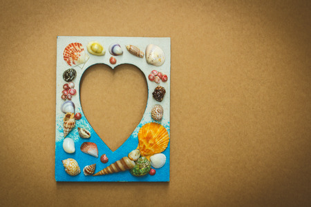 Picture frame made from sea shell on brown wall.の写真素材
