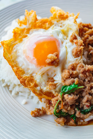 Rice topped with stir-fried pork and basil served with fried egg, Thai food.の写真素材