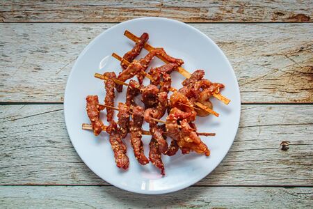 Fried sun dried pork style thai food on white plate.