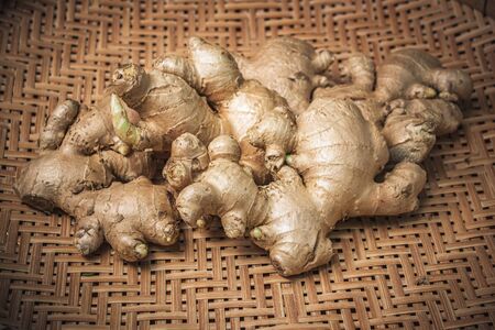 Fresh raw organic ginger root on bamboo tray background.