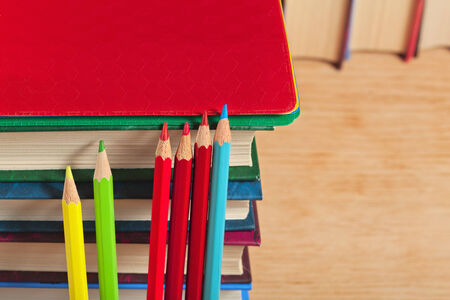 Pile of books and colored pencils on a wooden surface.の写真素材