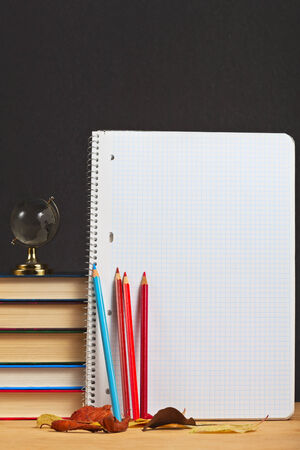 Notebook with colored pencils and globe on a wooden surface.の写真素材