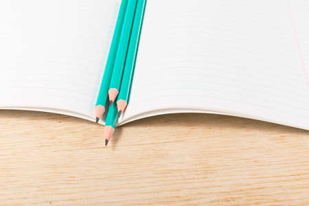 Notebook with pencils and on a wooden surface.の写真素材