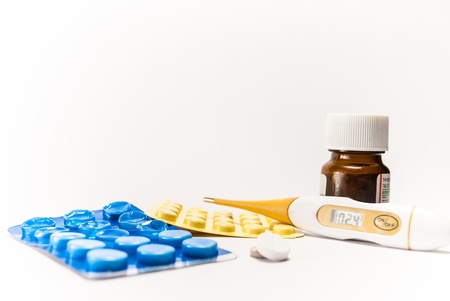 A thermometer reading high body tempature and tablets around it