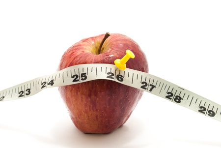fresh red farm apple and measuring tailor tape and a push pin over it on white isolated backgroundの写真素材