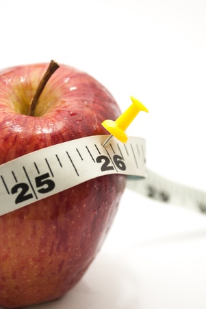 fresh red farm apple and measuring tailor tape and a push pin over it on white isolated backgroundの写真素材