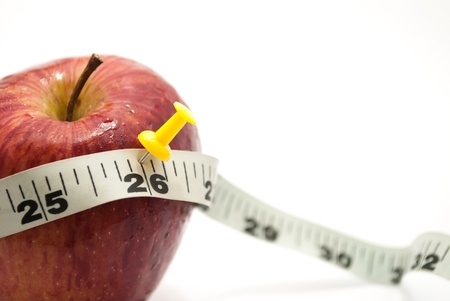 fresh red farm apple and measuring tailor tape and a push pin over it on white isolated backgroundの写真素材