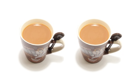 a coffee mug full of coffee with milk and sppon for mixing on white isolated backgroundの写真素材