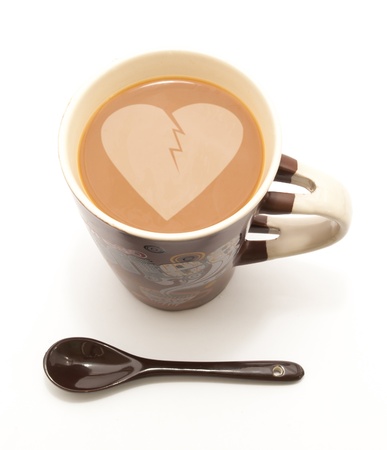 a coffee mug full of coffee with milk and sppon for mixing on white isolated backgroundの写真素材