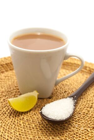 a spoon of sugar a lemon piece and a cup of tea on a jute woven saucerの写真素材
