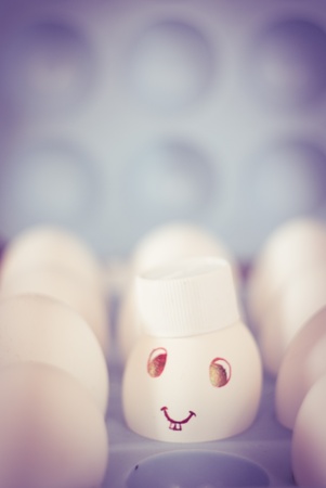 Egg with a smile and bunny teeth and cap in a blue egg trayの写真素材