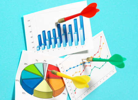 Darts sticking in graphs on blue background 
