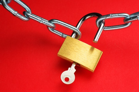 Unlocking padlock and chain on red background の写真素材