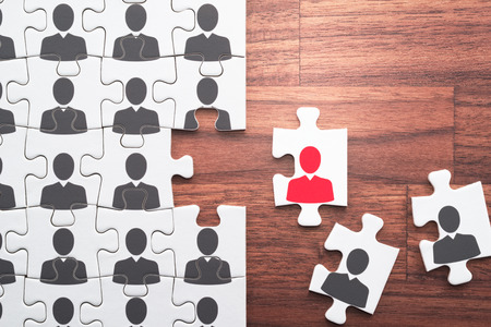 Human resource management... Selecting right people for organization's success. Personnel, employment and recruitment concept. Assembling jigsaw puzzle on wood desk.の写真素材