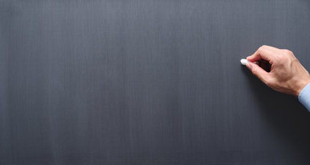 Teacher drawing on chalkboard. Blank blackboard background.  Hand holding chalk.
