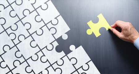 Finding business solution. Businessman drawing puzzle pieces on chalkboard.の写真素材