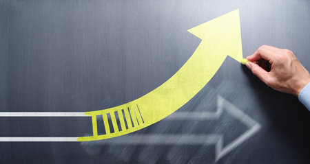 Changing business management concept. Businessman erasing white arrow and drawing yellow arrow on chalkboard.の写真素材