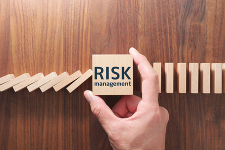 Concept image of stopping domino effect. Risk management. Putting wood cube and stopping domino.の写真素材