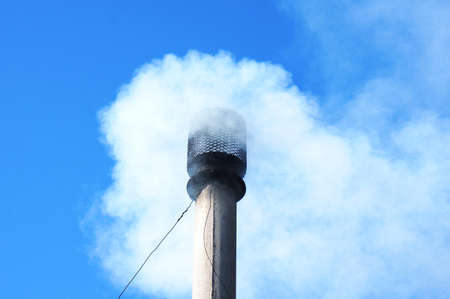 smoke from the chimney pipe in the blue skyの写真素材