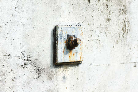 Anchor bolt on the white-painted concrete wall