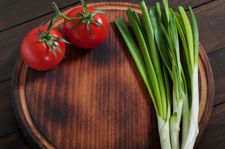 Natural products vegetables tomatoes and green onions on an old kitchen board.の写真素材