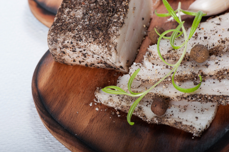Traditional Ukrainian lard with black pepper and garlic, on the old wooden background.の写真素材