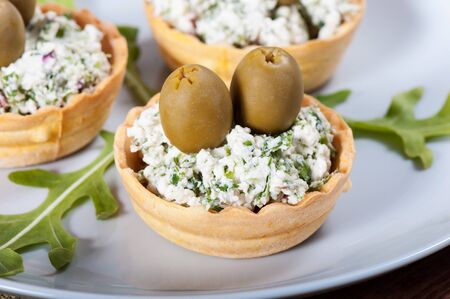 Cheese with greens and olives, arugula on a light plate.の写真素材
