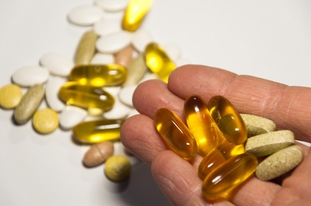 Hand holds quality food pills as nutrition supplements helps fit your health. Isolated on white...