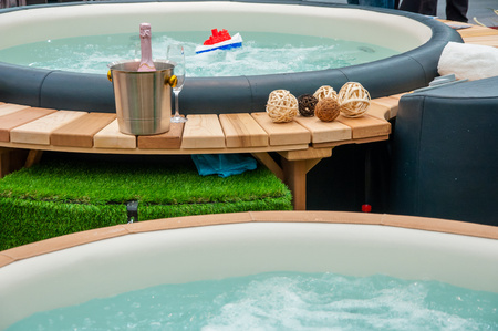 Detail view of luxury beautiful hot tub for relaxing, with decoration, towels, bottle of wine in nice interior.の写真素材