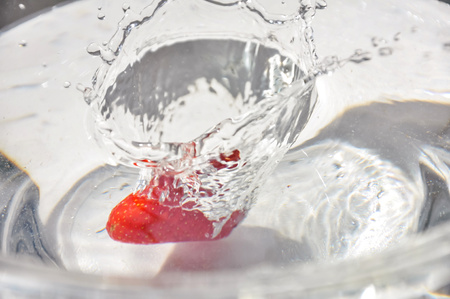 Falling strawberies in water. Strawberry underwater. Red sweet fresh fruit splashing into waterの写真素材