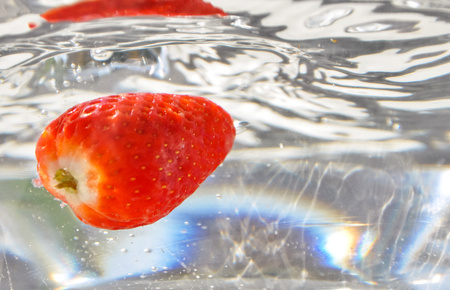 Falling strawberies in water. Strawberry underwater. Red sweet fresh fruit splashing into waterの写真素材