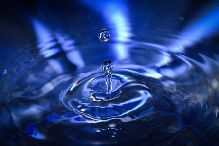 Close up of a blue water drop, macro photography. Falling water drop into water making crown.