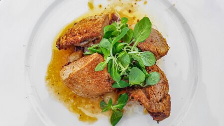 Luxury roasted pork tenderloin with lettuce served on plate.