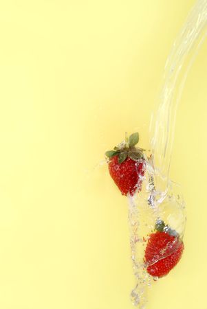 strawberry fall with water isolated on yellowの写真素材