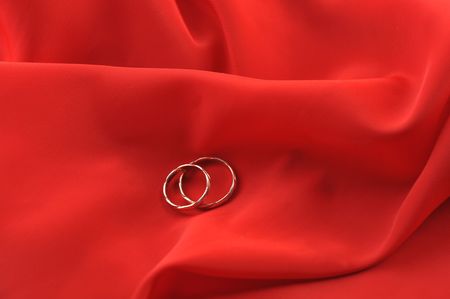 red graceful fabric and  gold wedding rings close upの写真素材