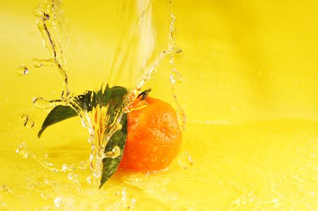 tangerine and water splashes on yellow, close upの写真素材