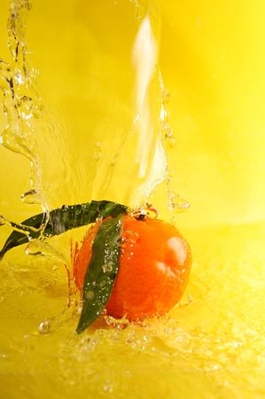 tangerine and water splashes on yellow, close upの写真素材