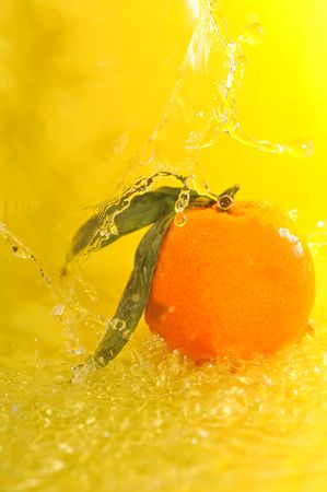 tangerine and water splashes on yellow close upの写真素材