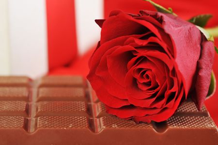 beautiful red rose, gift and chocolate  on red close upの写真素材