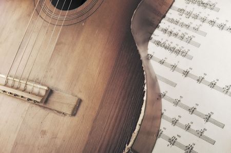 Acoustic guitar laying across sheet musicの写真素材