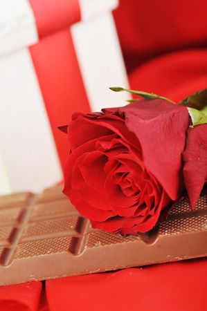 beautiful red rose, gift and chocolate  on red close upの写真素材