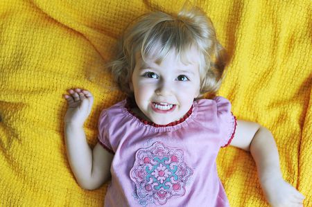 Beautiful little girl  lying on  bed at  house