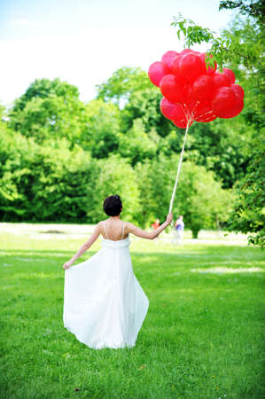 bride in white wedding dress goes on  green fieldの写真素材