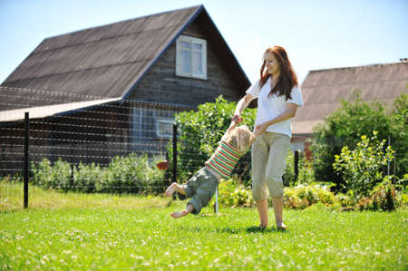 Beautiful young mother with her  daughter playing on grass . summer.の写真素材